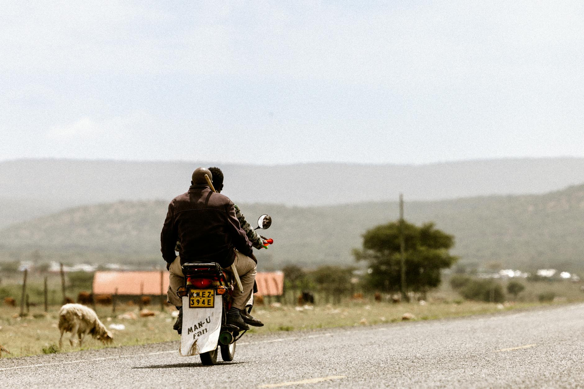 Dwie osoby jadą motocyklem wiejską drogą wśród malowniczych wzgórz