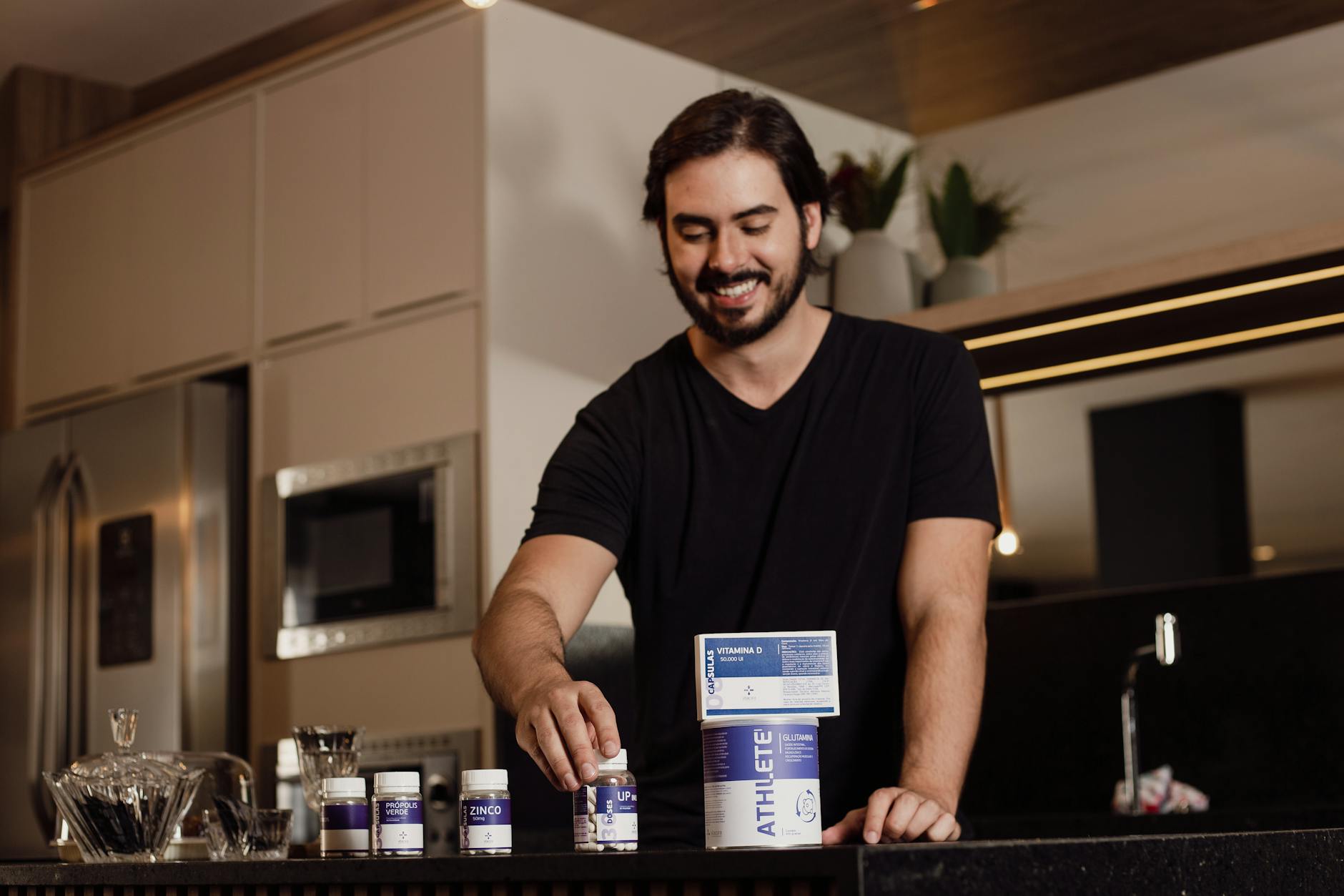 Uśmiechnięty mężczyzna układa suplementy diety na blacie w kuchni
