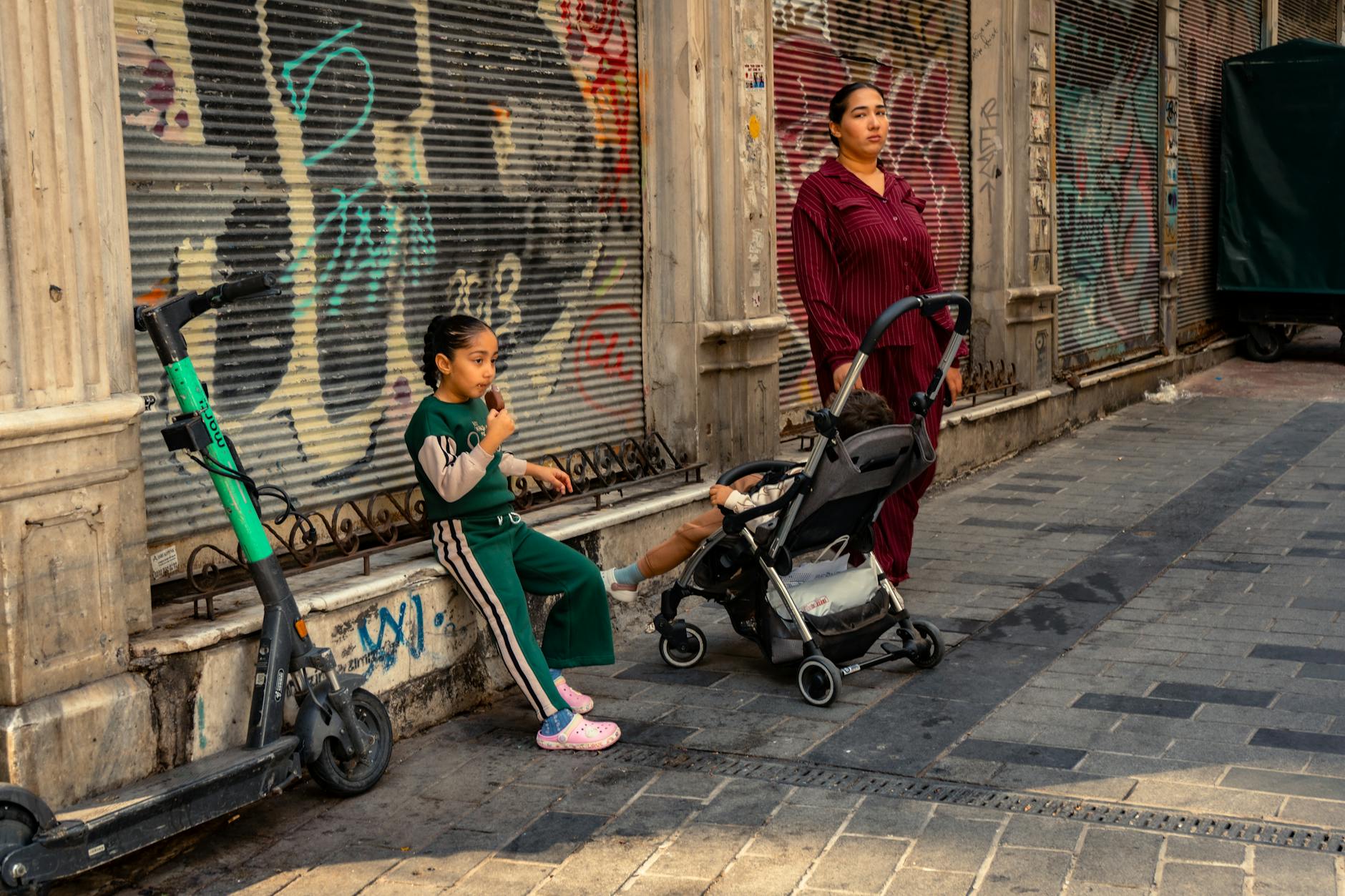 Mama z dziećmi je lody przy kolorowym graffiti w uliczce Marrakeszu