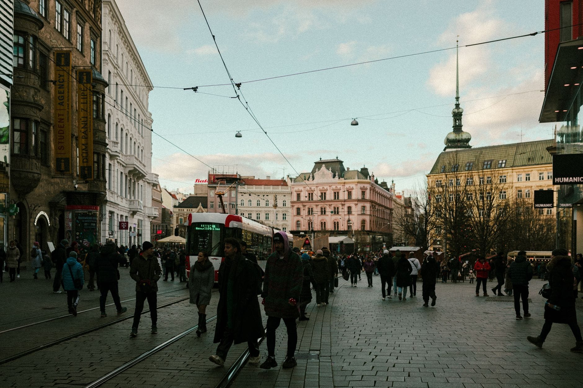 Ruchliwa ulica w centrum Brna z zabytkowymi kamienicami i przechodniami