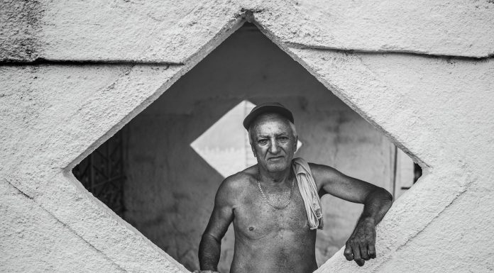 Czarno-biały portret starszego Kubańczyka w geometrycznym otworze muru