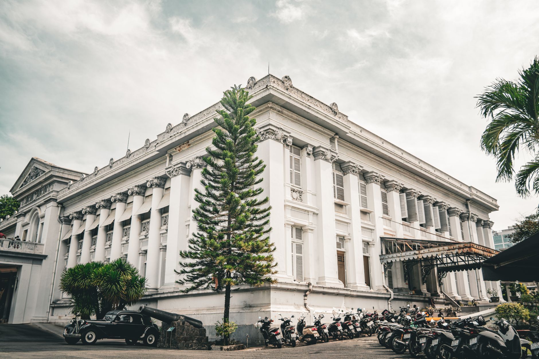 Muzeum Ho Chi Minh City o neoklasycznej fasadzie i motorbikach z przodu