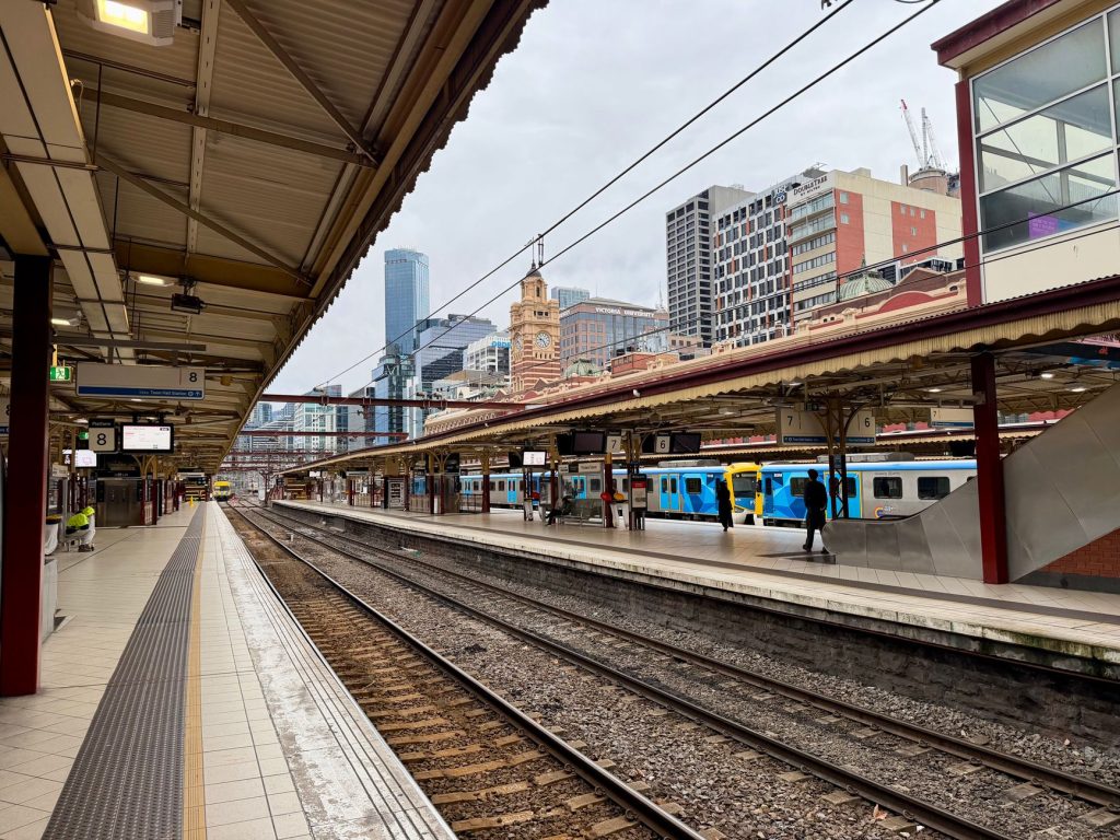 Perony stacji Flinders Street w Melbourne z pociągami i pasażerami